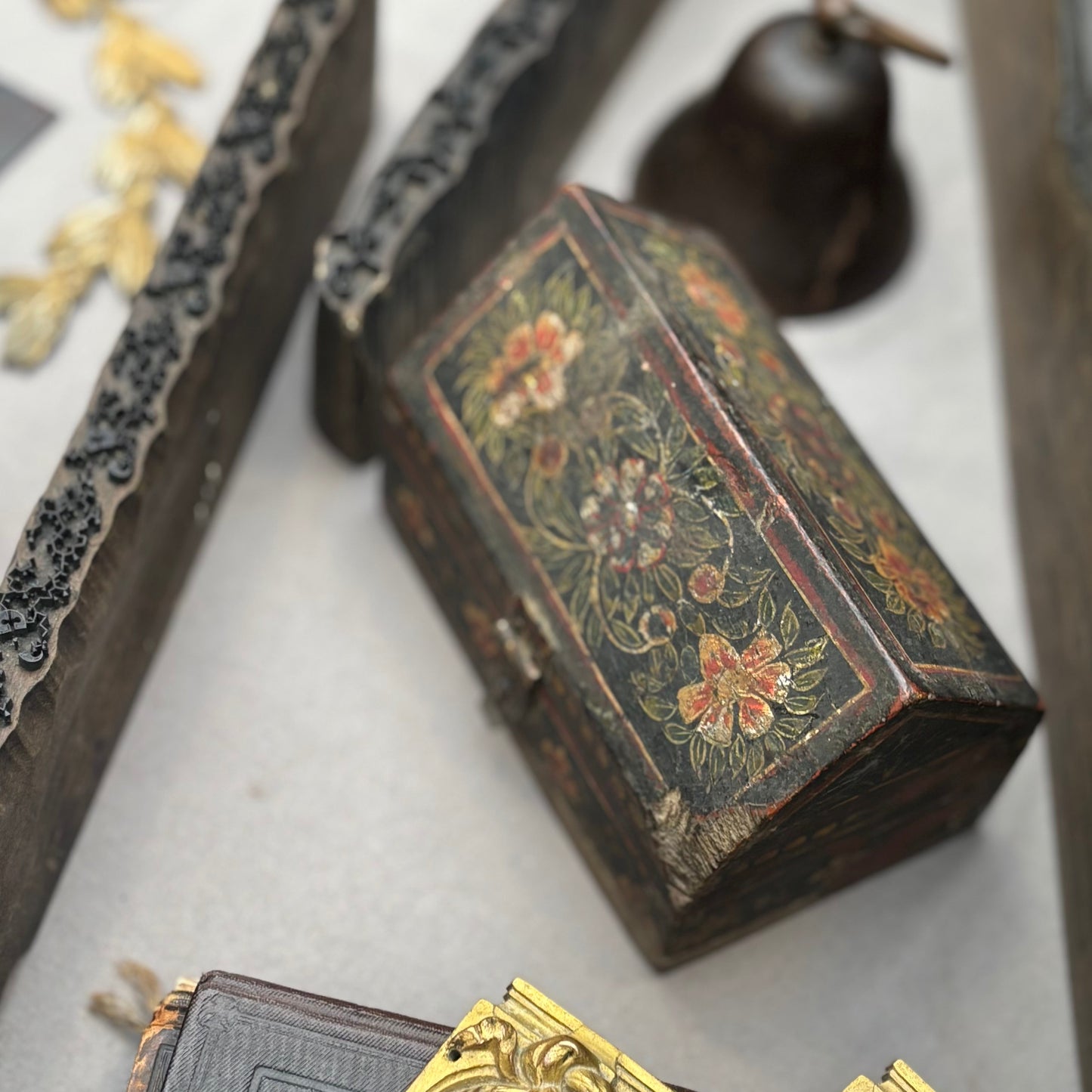Decorative wooden box with floral patterns and ornate gold objects on a marble surface.