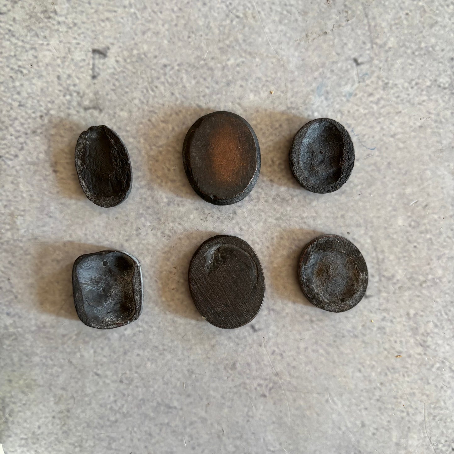 Collection of dark brown oval Metal Grand Tour Intaglios Seals engraved designs on a light grey surface