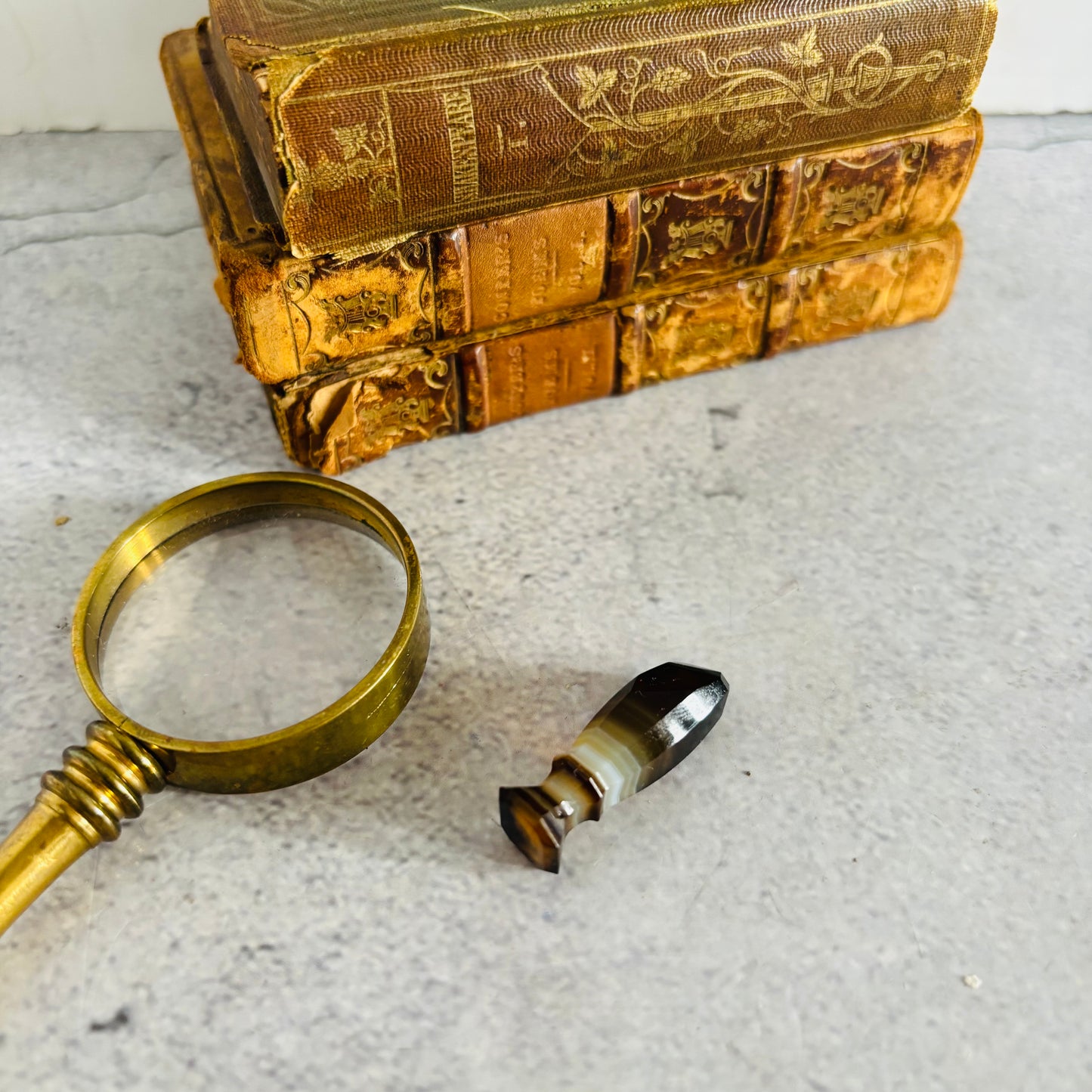 Miniature stack of old books with a magnifying glass and agate was sea stamp