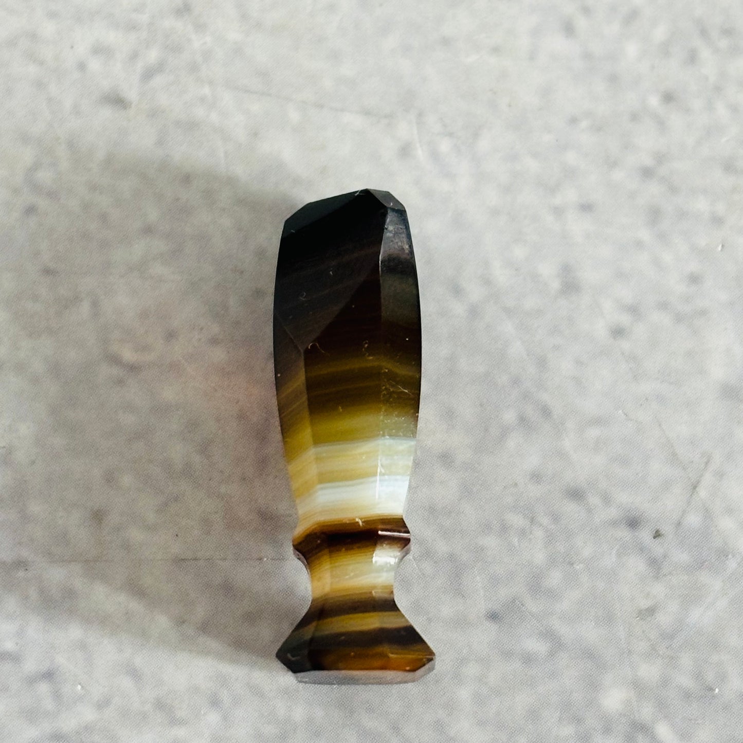 Banded agate stone wax seal stamp on a textured grey background