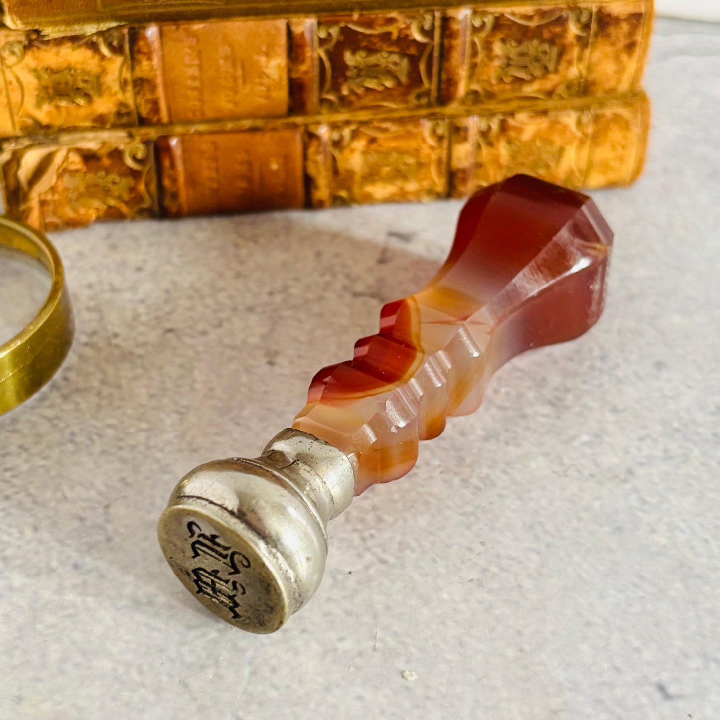 Decorative wax seal stamp with agate handle and metal base on a textured surface