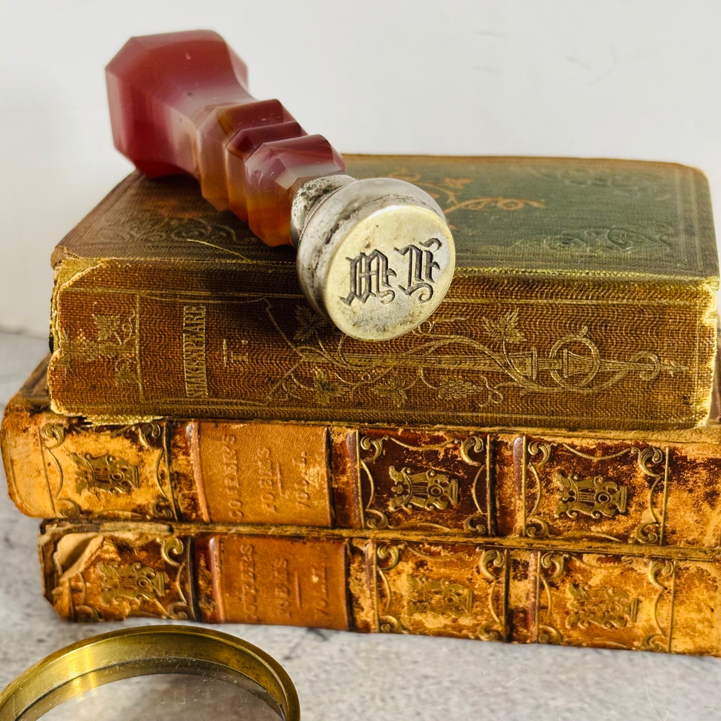 Stack of old books with a decorative seal on top and a magnifying glass in the foreground.