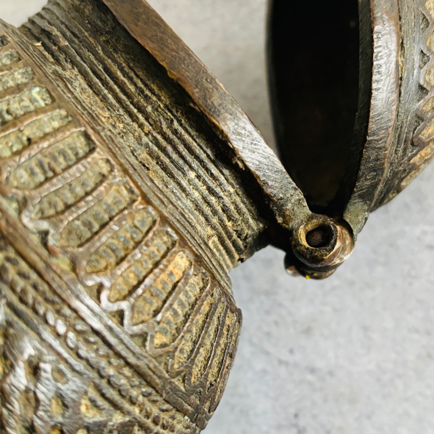 Close-up of an ornate metal object with intricate designs on a textured surface