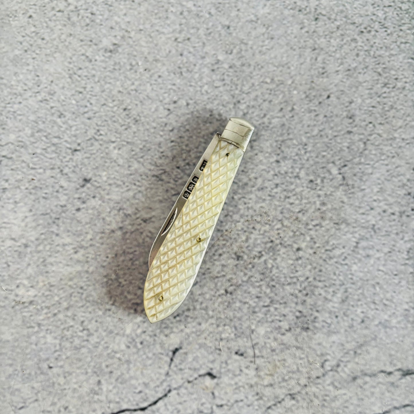 Silver pocket knife with textured handle on a gray surface