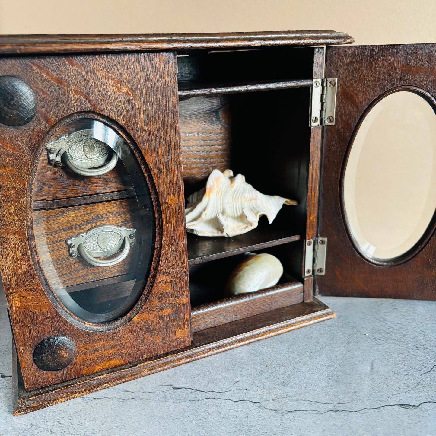 Wooden box with circular cutouts containing seashells on a textured surface