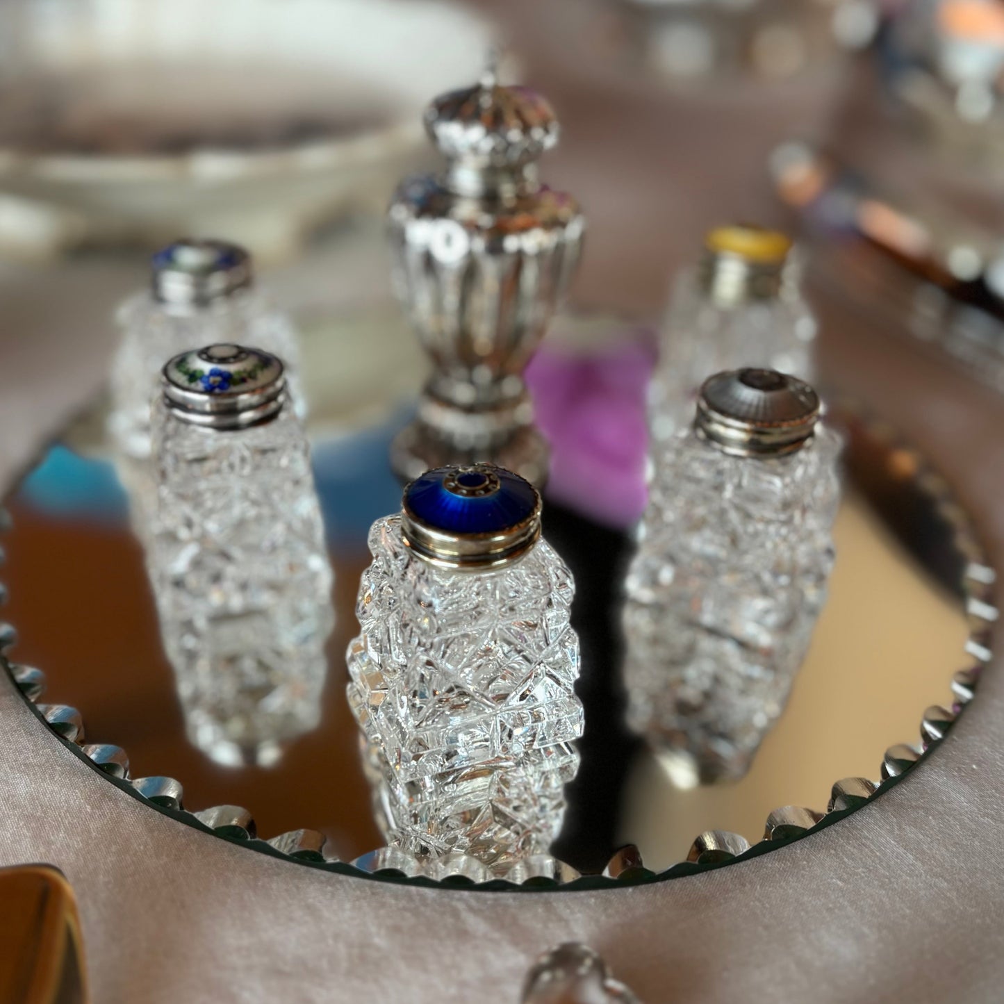 Decorative salt pepper bottles with crystal designs on a reflective surface