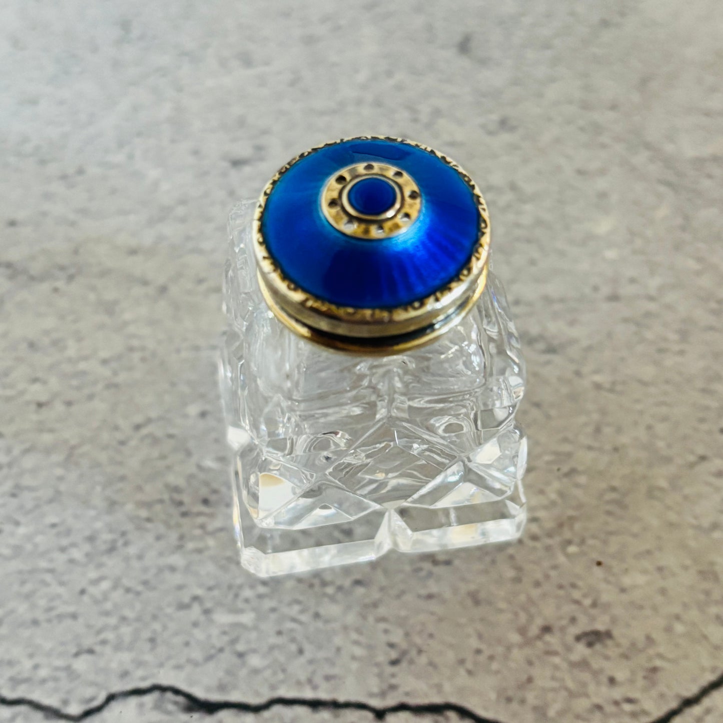 Glass and silver guilloche enamel salt and pepper bottle with colourful stopper on a grey surface
