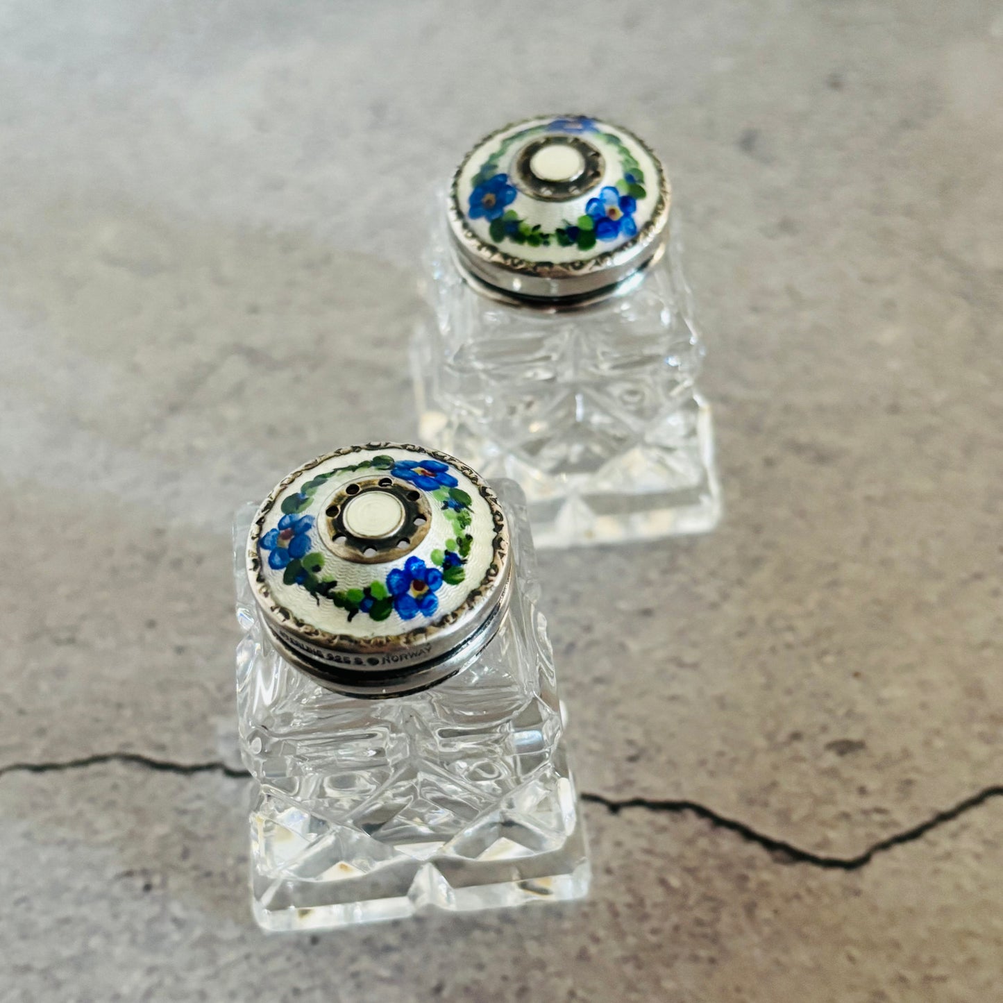 Glass and Silver floral guilloche enamel salt and pepper bottle with colourful stopper on a grey surface