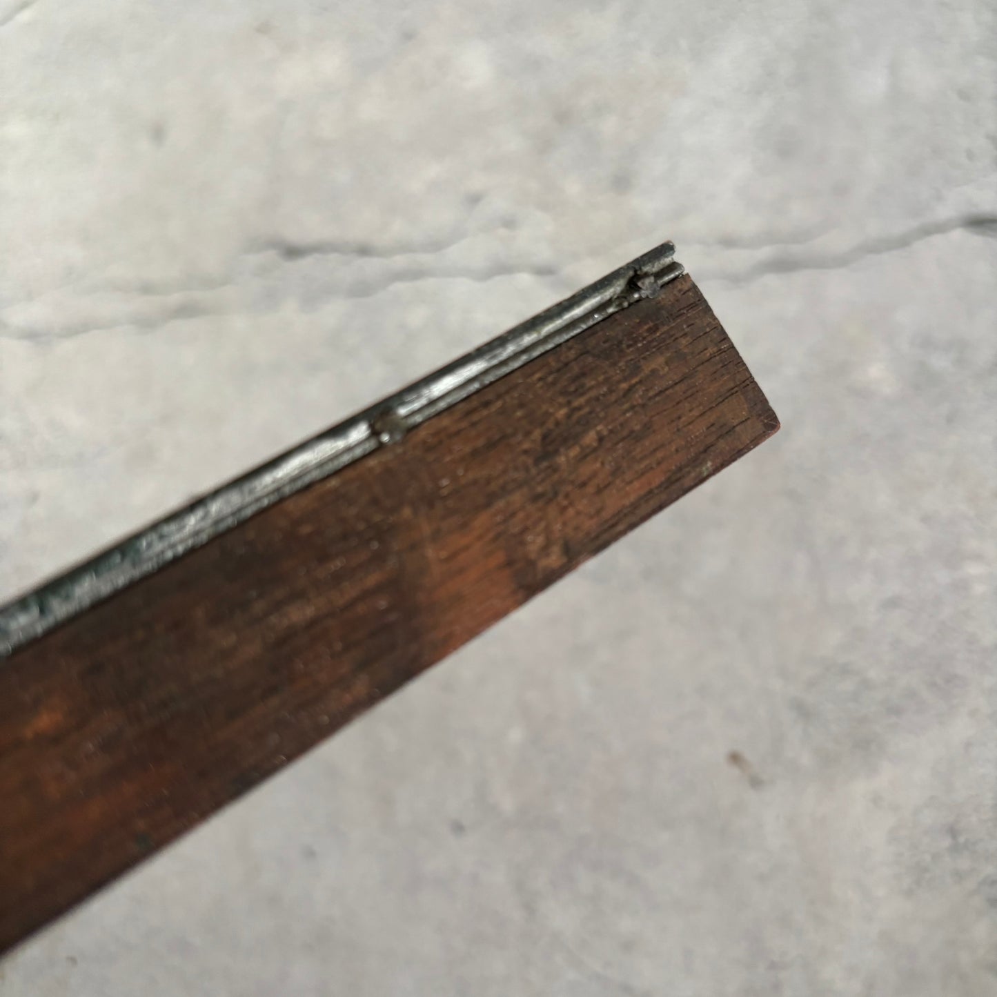 Close-up of a wooden object with metal edge on a marble surface