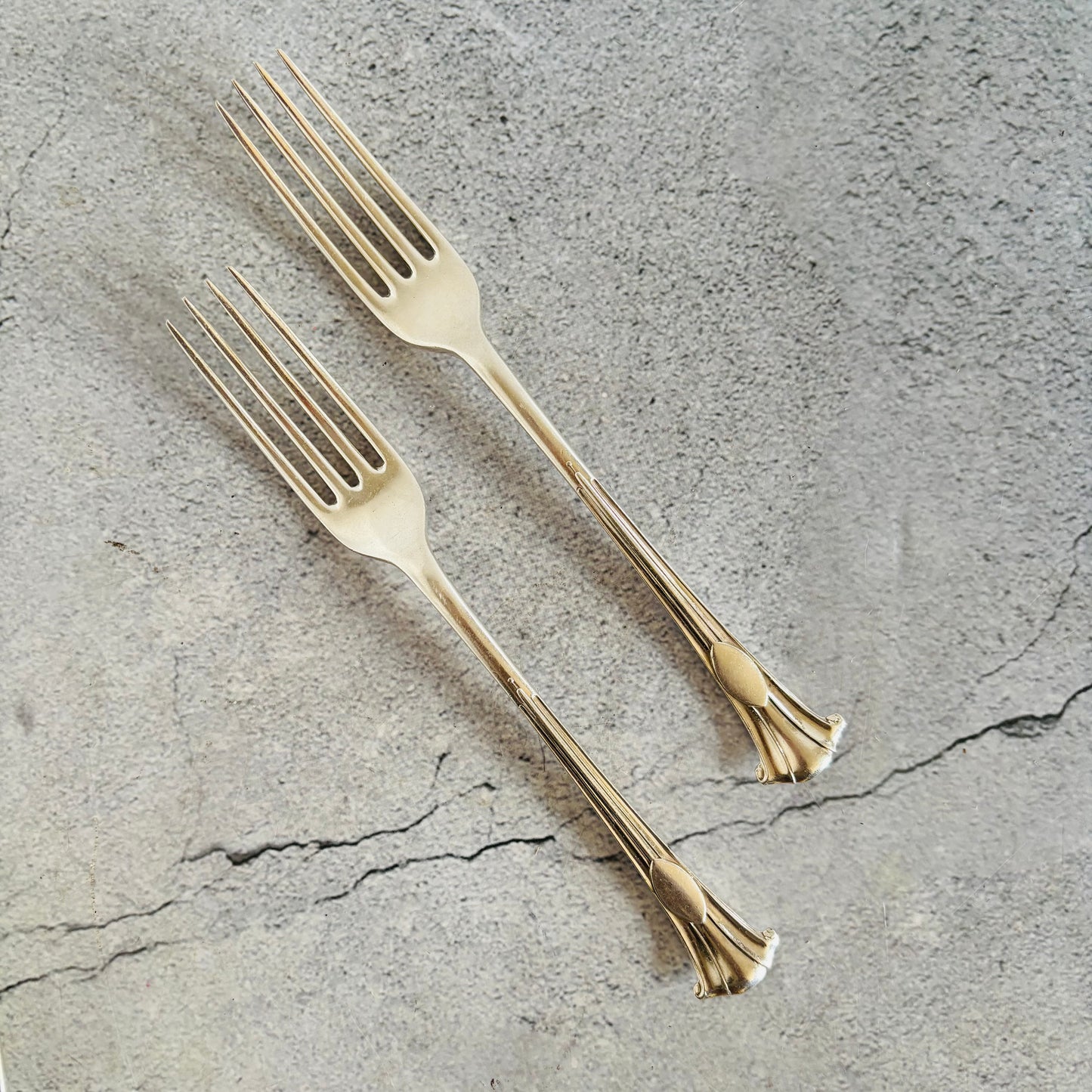 Two silver forks on a textured gray surface