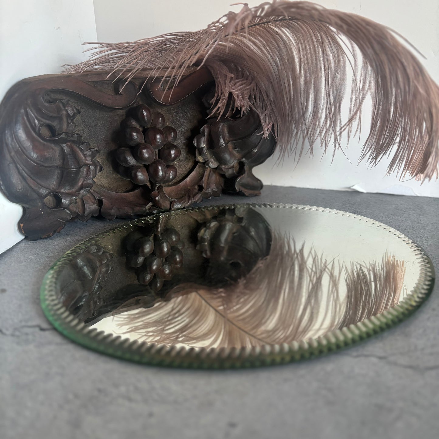 Decorative wooden fragment, feathers, and a Antique Oval Sorcerers Mirror Mat