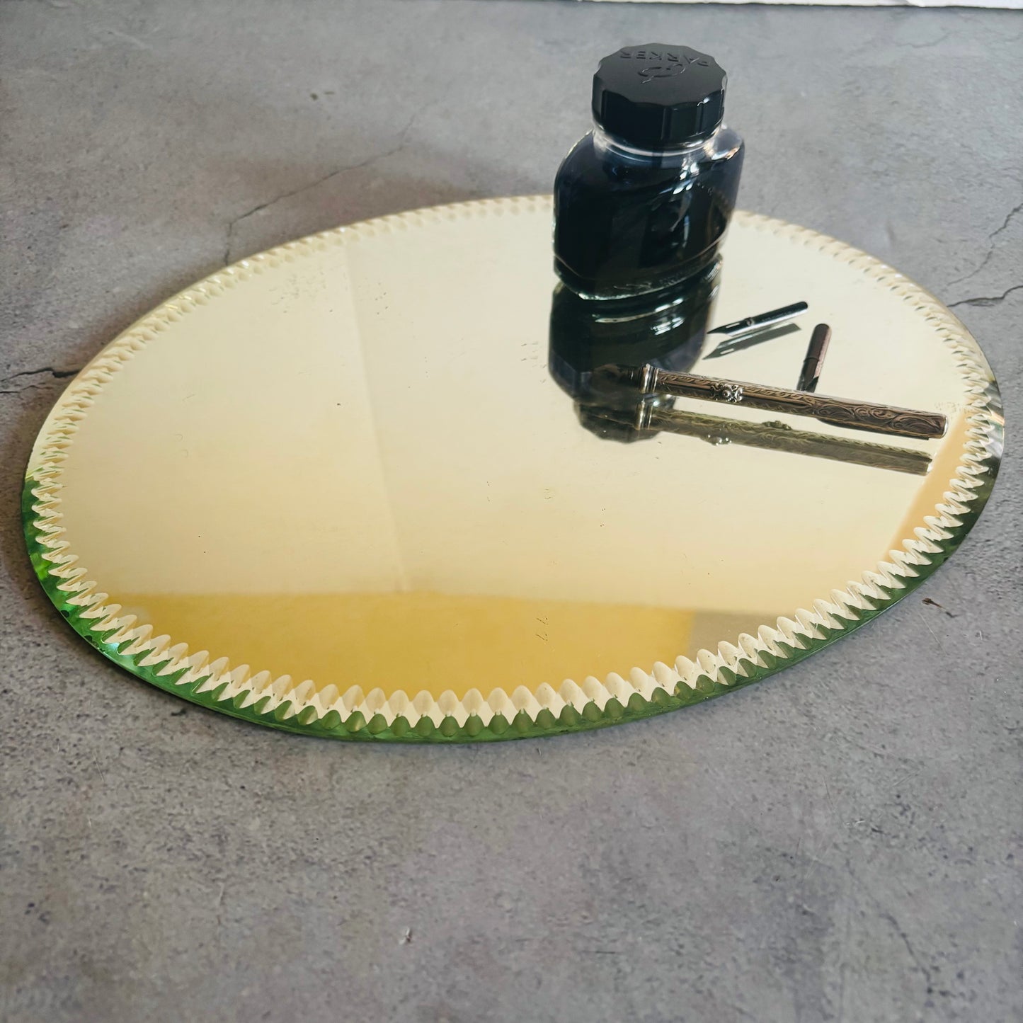Antique Oval Sorcerers Mirror Mat | Gypsy Mirror Display Plateau with a bottle and tools on a concrete surface