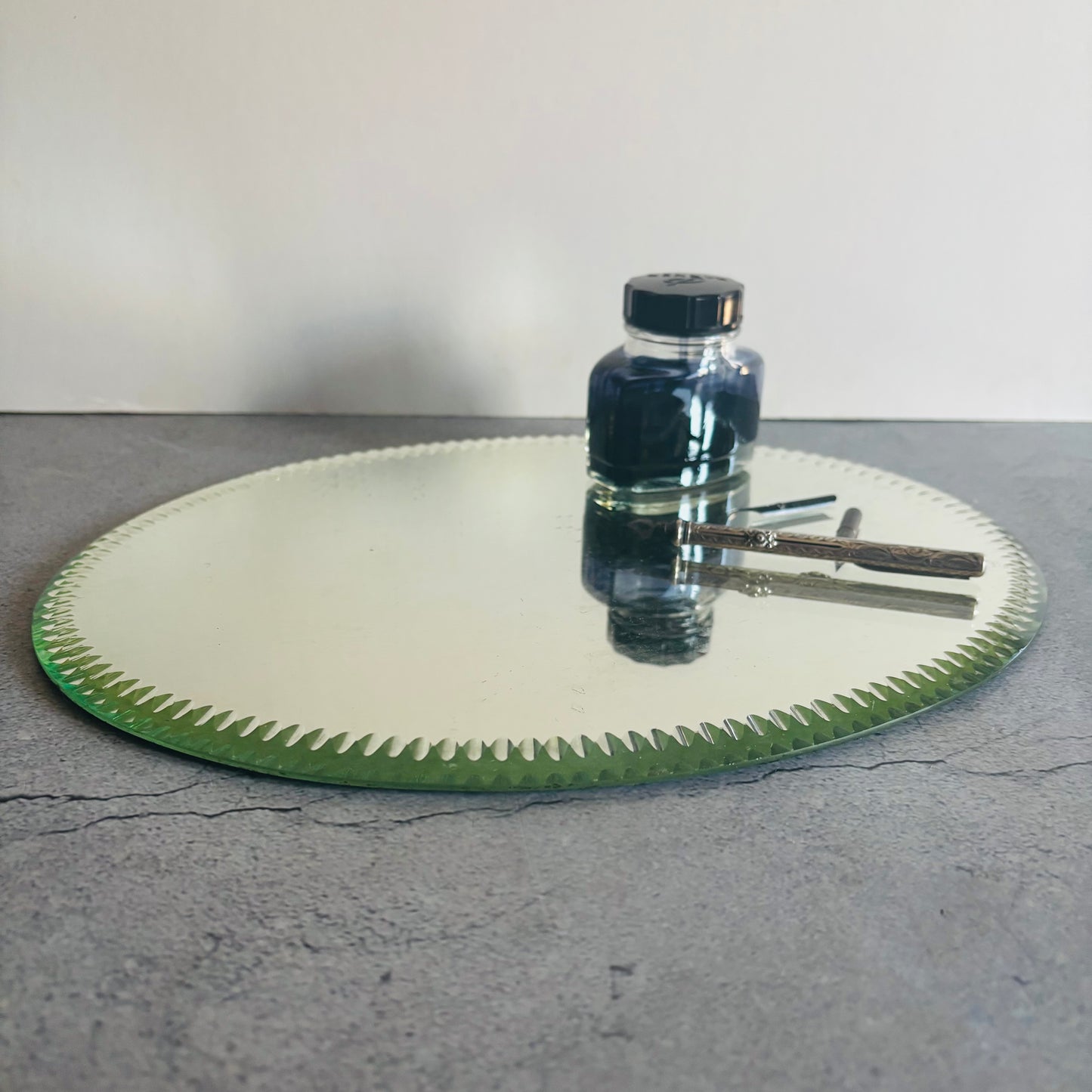 Antique Oval Sorcerers Mirror Mat Gypsy Mirror with a bottle of ink on a grey surface
