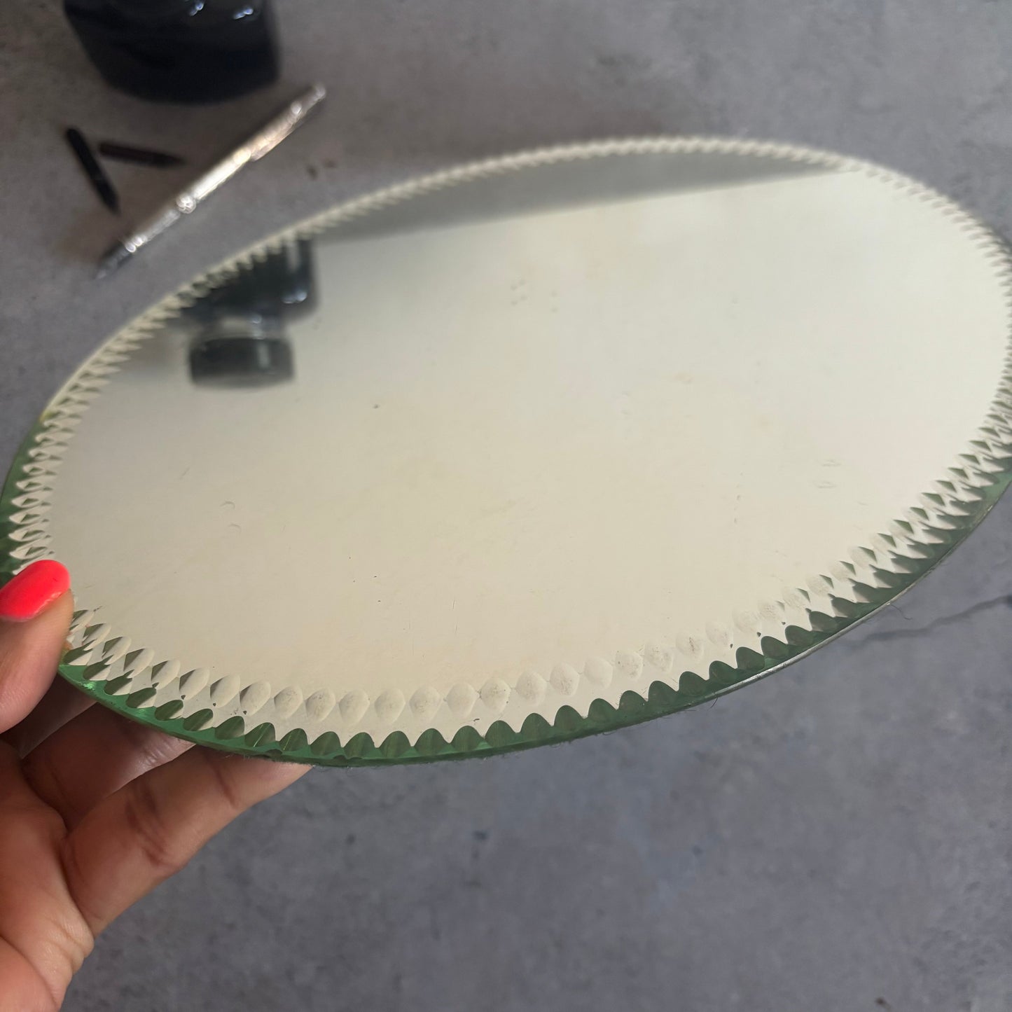 Close-up of an Oval Sorcerers Mirror with textured edge held by a hand.