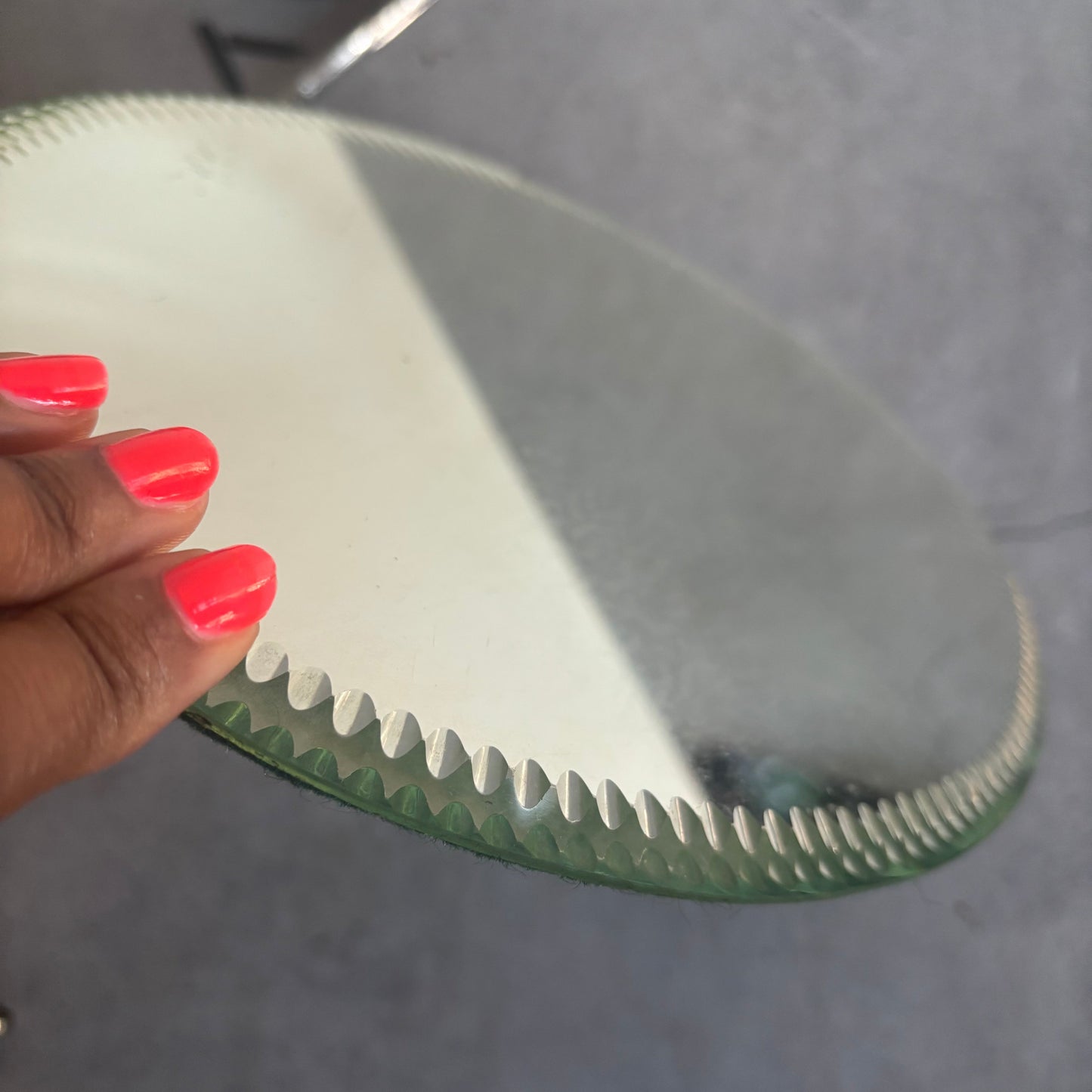 Close-up of a hand with red nail polish holding a Antique Sorcerers Mirror