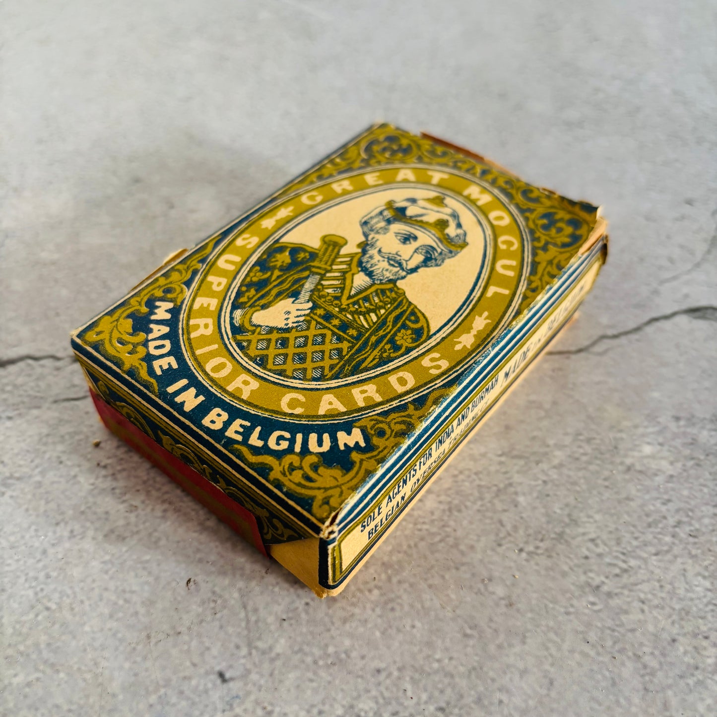 Playing card box with decorative design and text on a concrete surface
