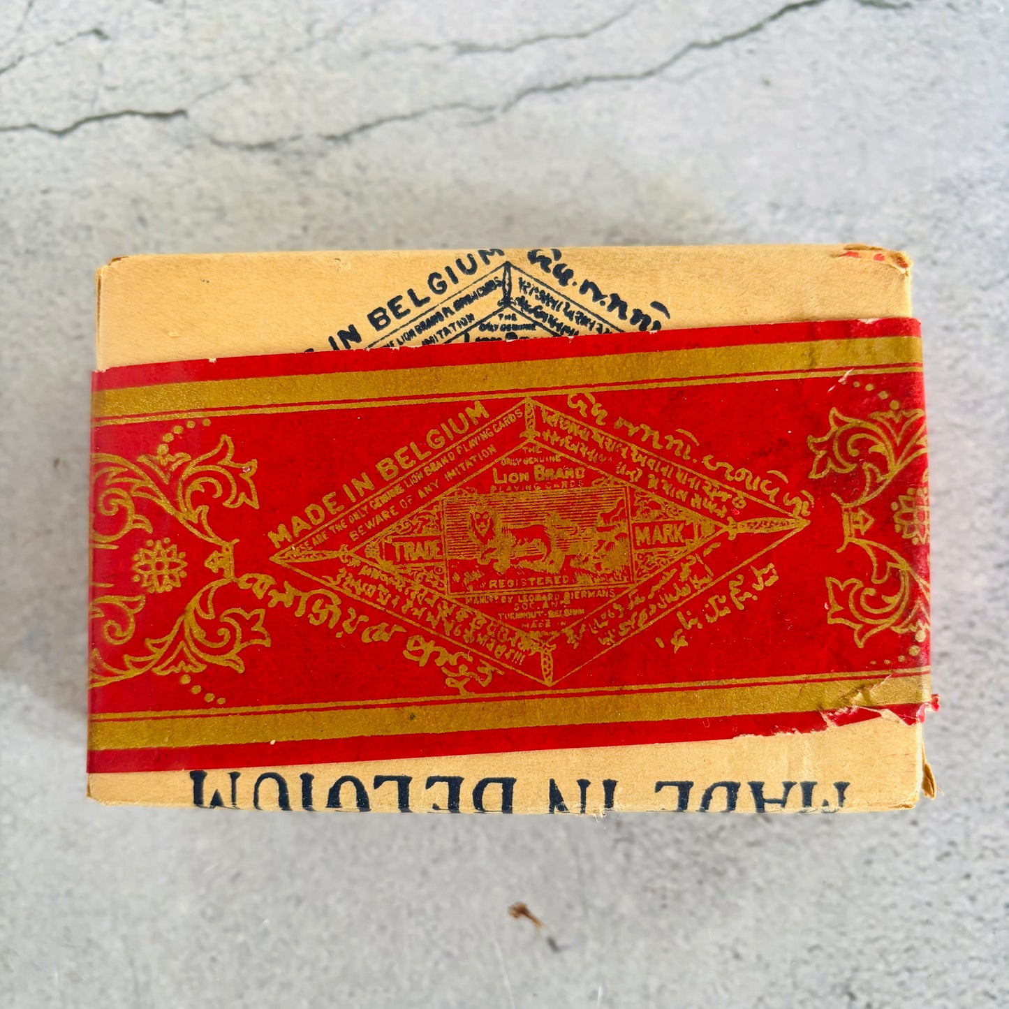 Vintage playing cards packaging with red and gold design on a grey surface