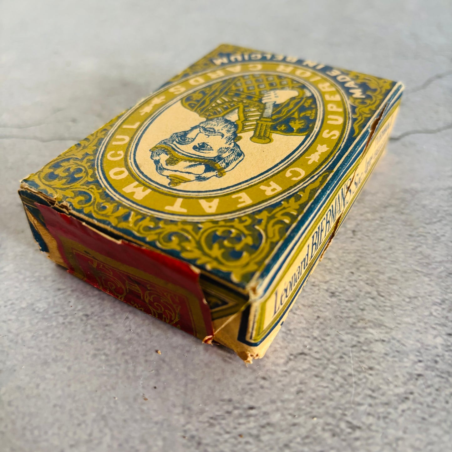 Vintage playing card box with decorative design on a grey surface