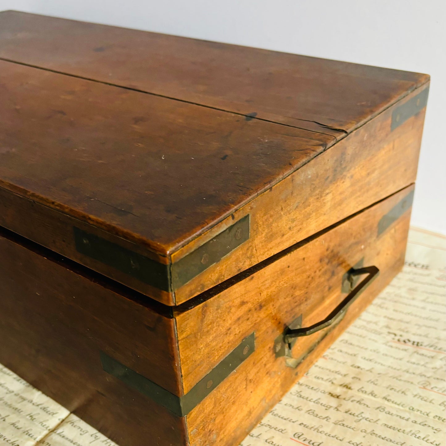Wooden box with brass handles on a surface with text