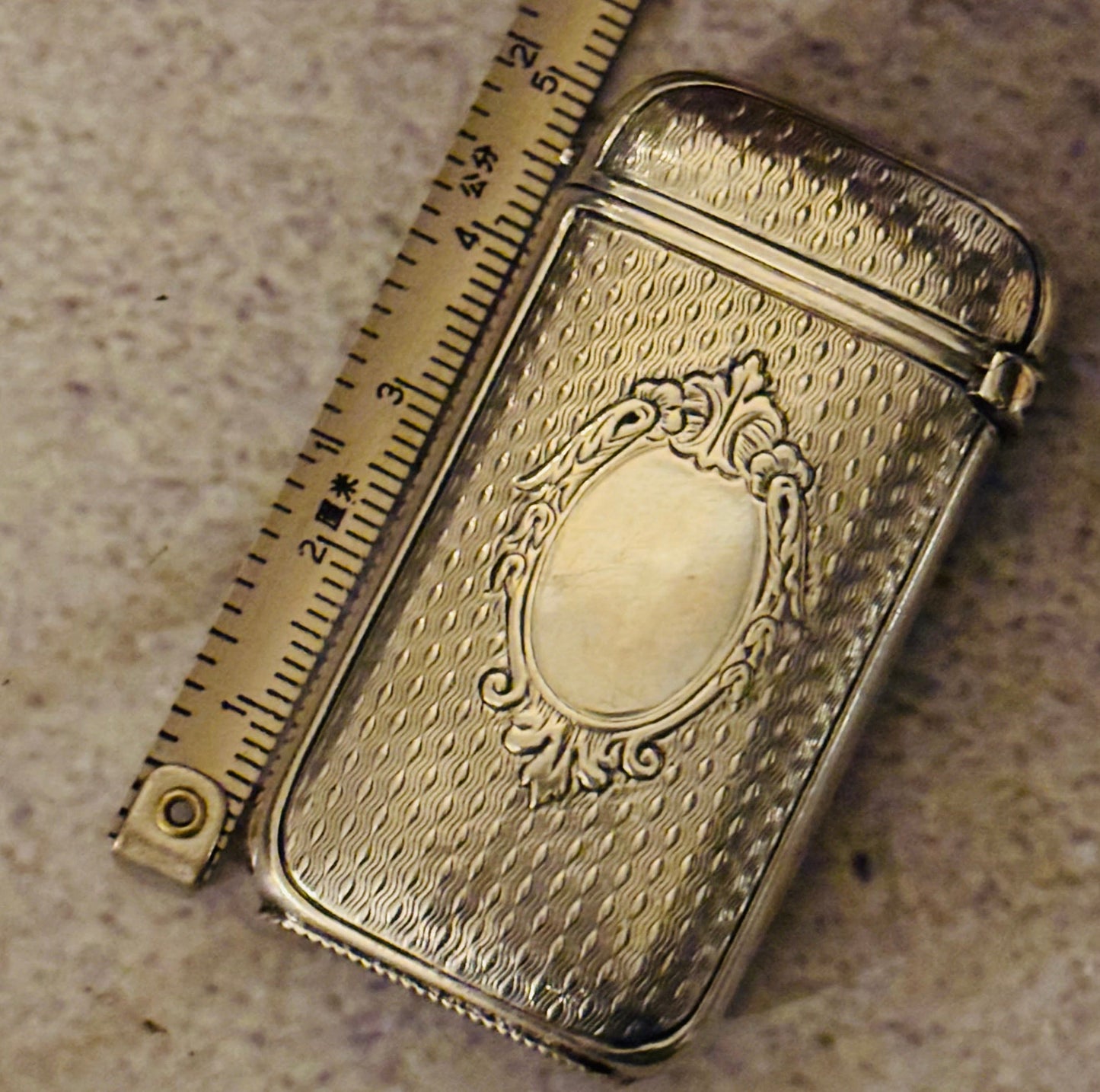 Rare Small Antique Silver Vesta Case Match Striker | French with decorative emblem on a textured surface next to a ruler for scale.