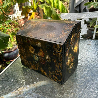 Decorative black box with floral patterns on a glass surface outdoors