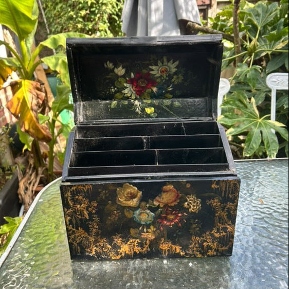 Victorian Paper Mache Lacquer Stationery Box  with hand painted floral patterns on a glass table outdoors.