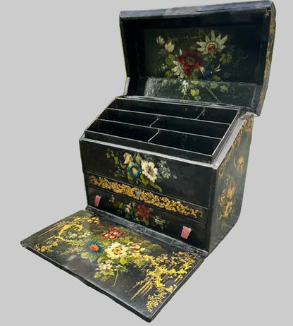 Victorian Paper Mache Lacquer Stationery Box  with hand painted floral patterns on a glass table outdoors.