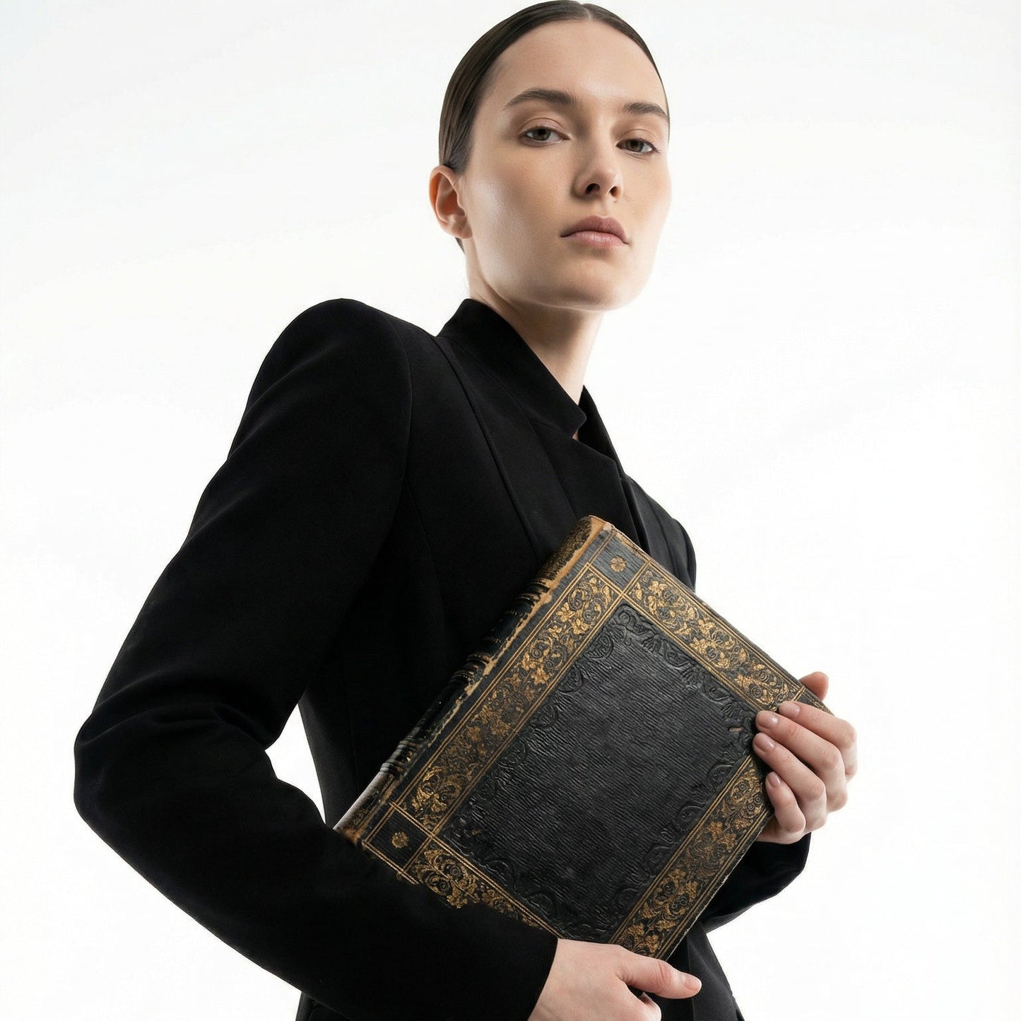 Person holding a black book with gold detailing against a white background