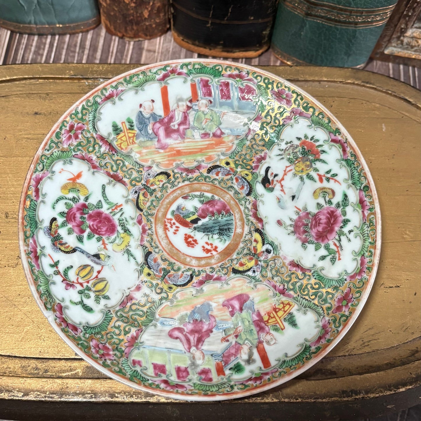 Decorative plate with intricate patterns on a wooden surface with books in the background