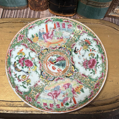 Decorative plate with intricate patterns on a wooden surface with books in the background
