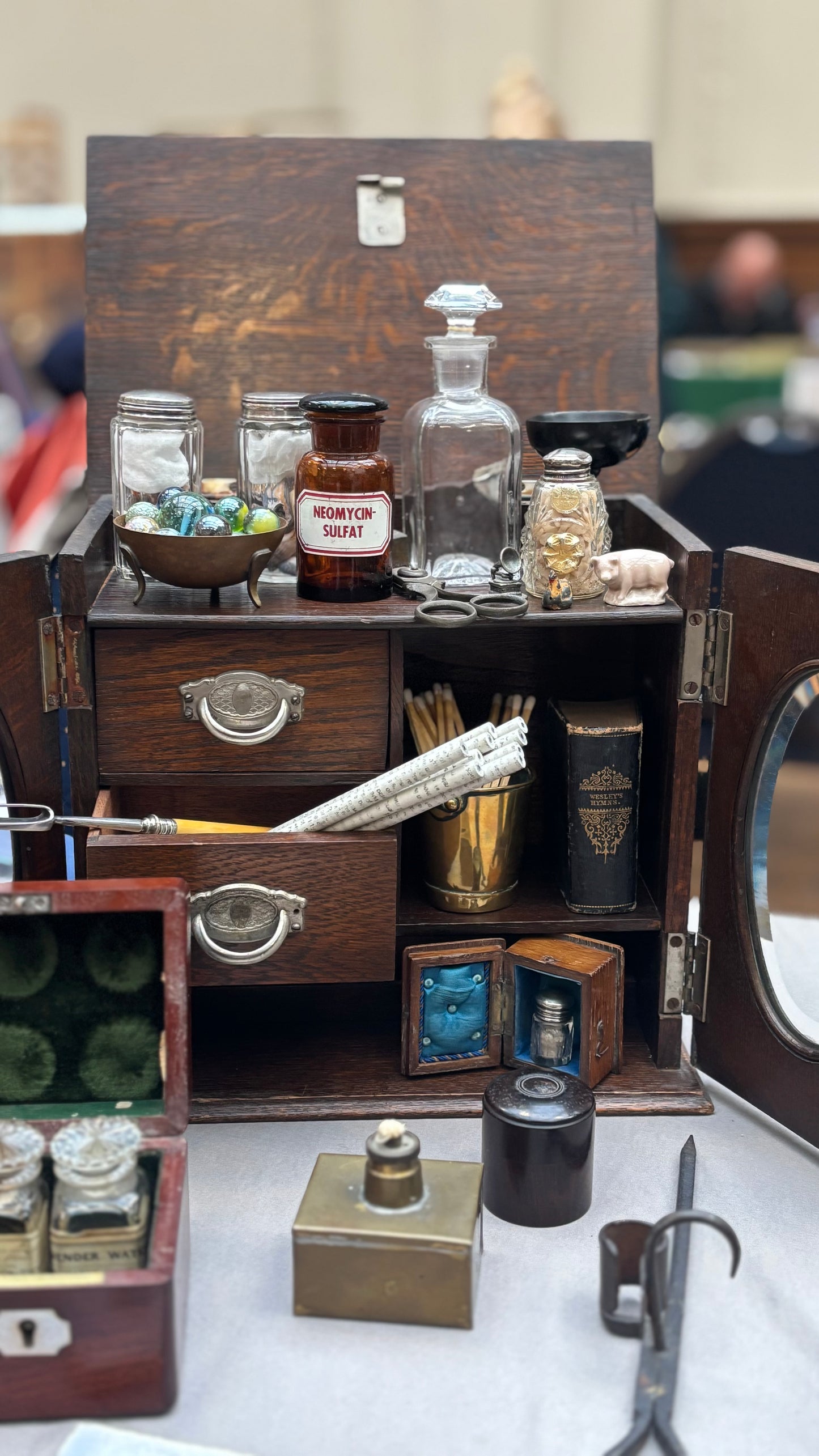 Vintage-style apothecary set with wooden drawers, bottles, and tools on a white surface.