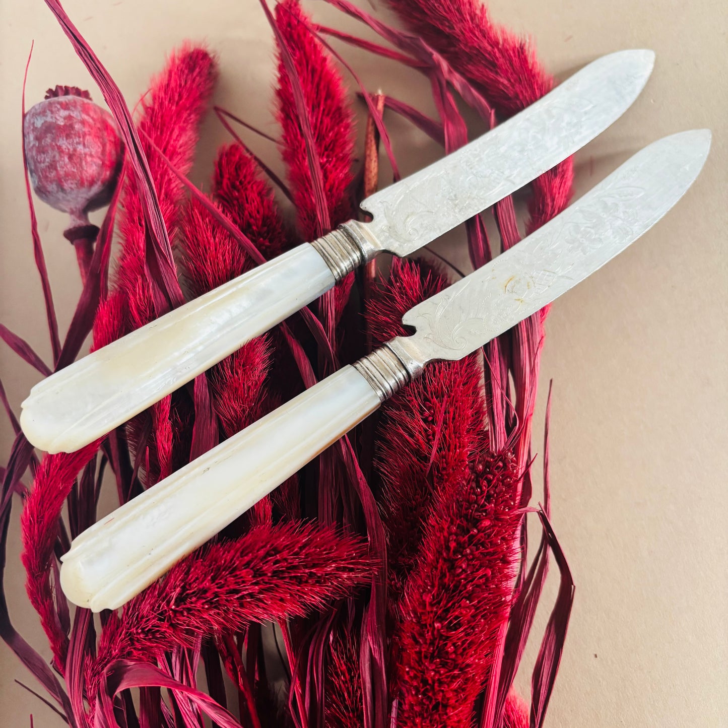 Two knives with white handles on red floral background