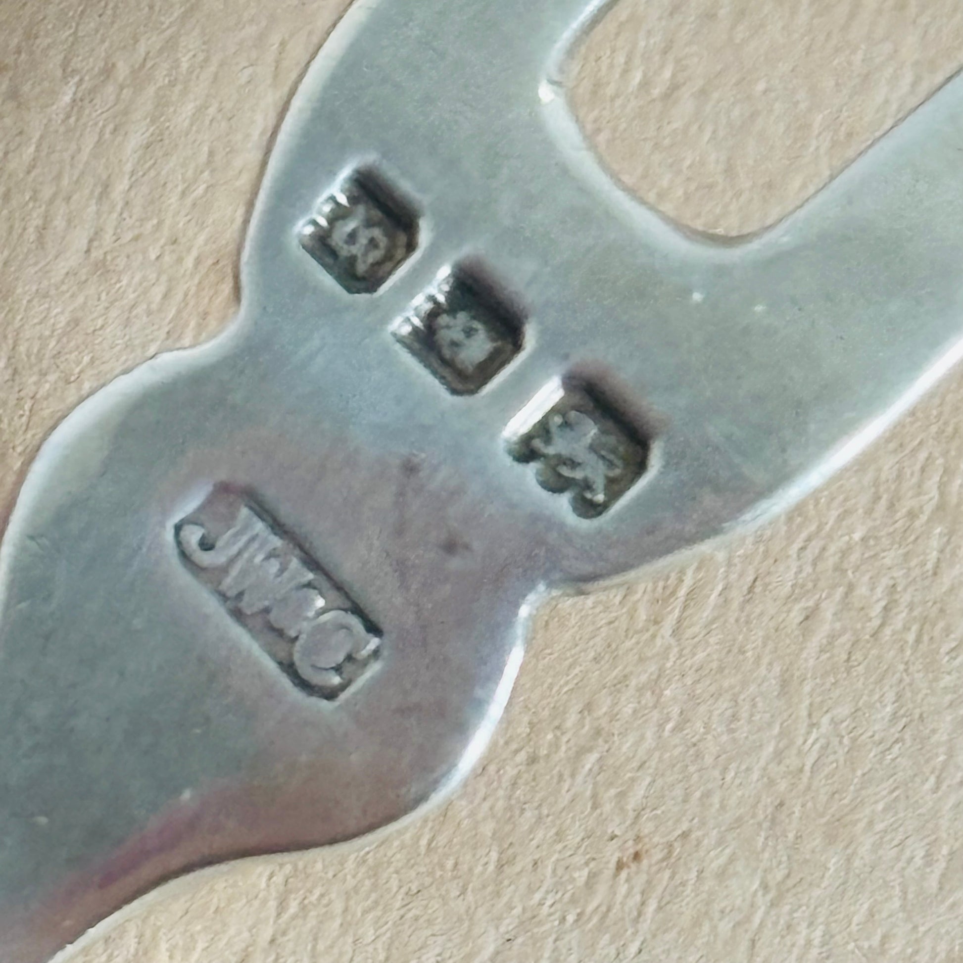Close-up of a silver fork with visible hallmarks on a beige background