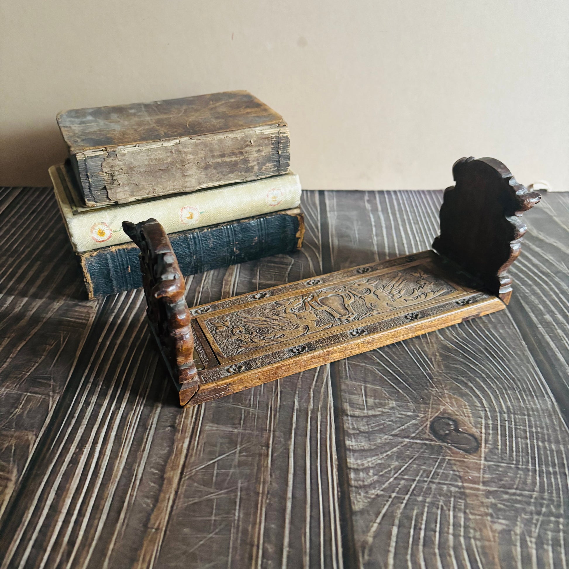 Stack of vintage books with a wooden book stand on a textured surface