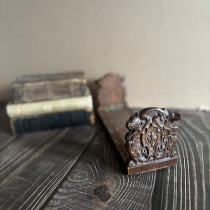 Decorative wooden bracket on a wooden surface with a blurred background