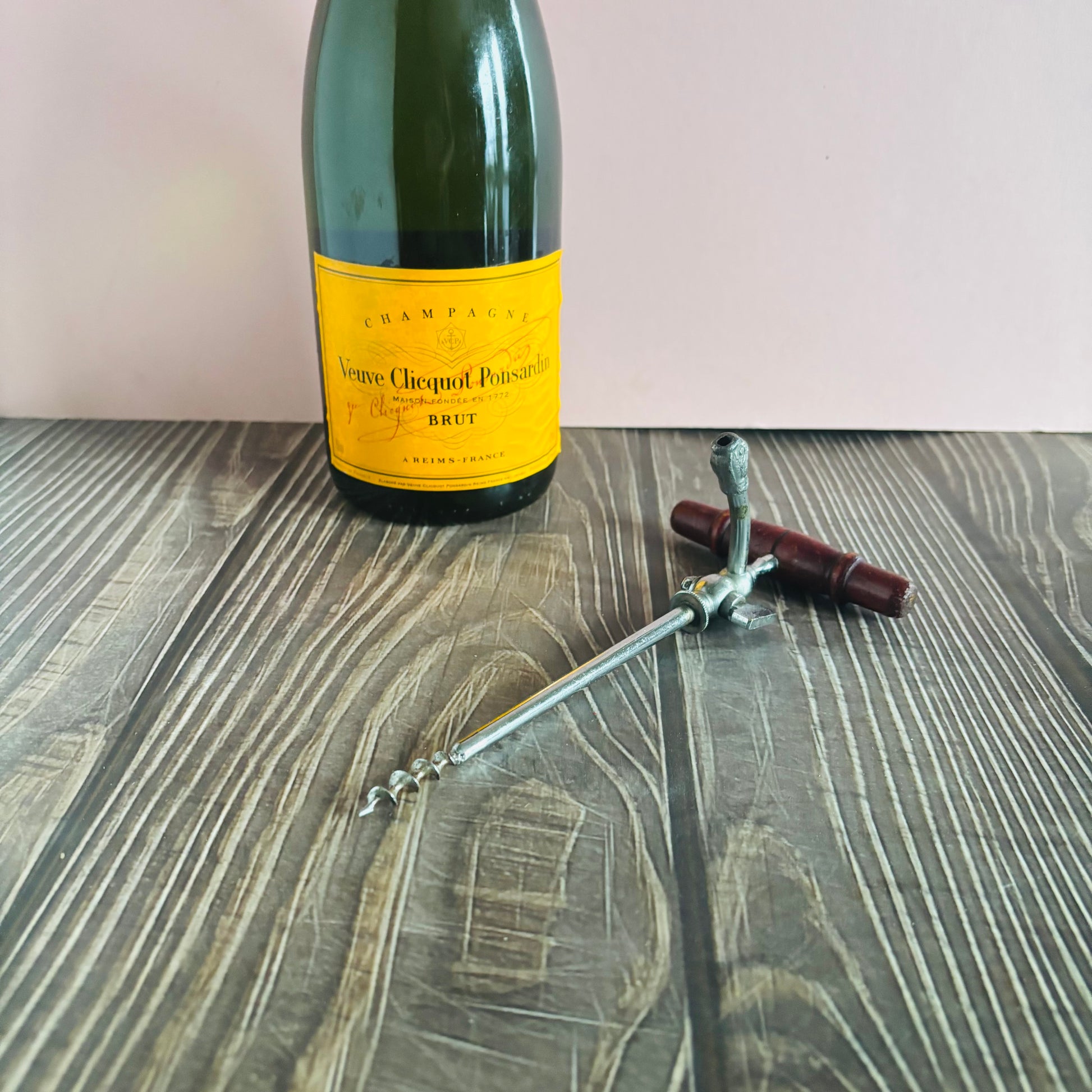 Veuve Clicquot champagne bottle with a corkscrew on a wooden surface