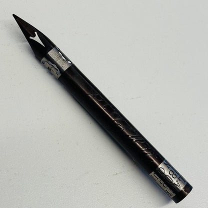 A black pen nib with silver engraved details and a silver nib, photographed diagonally on a light gray background.