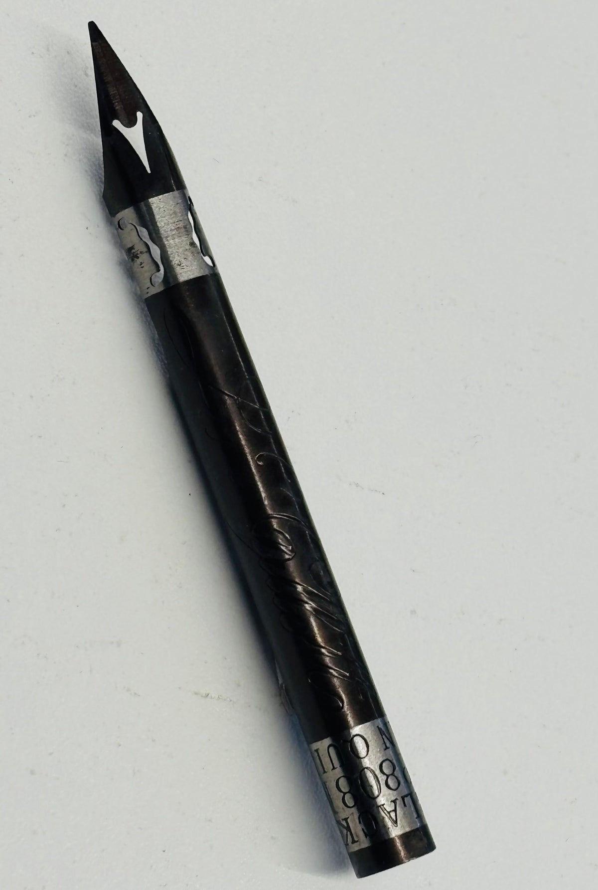 A black dip pen with silver metal accents and engraved details, shown diagonally on a plain light gray background.