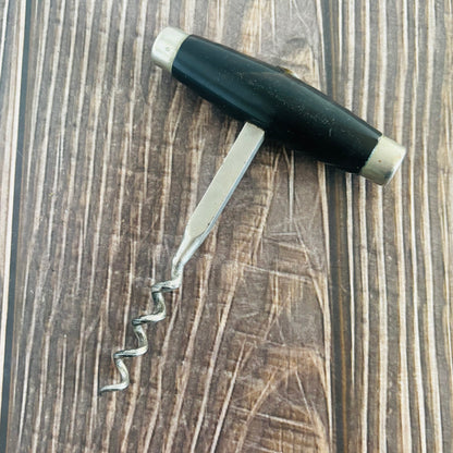 Corkscrew with black handle on a wooden surface