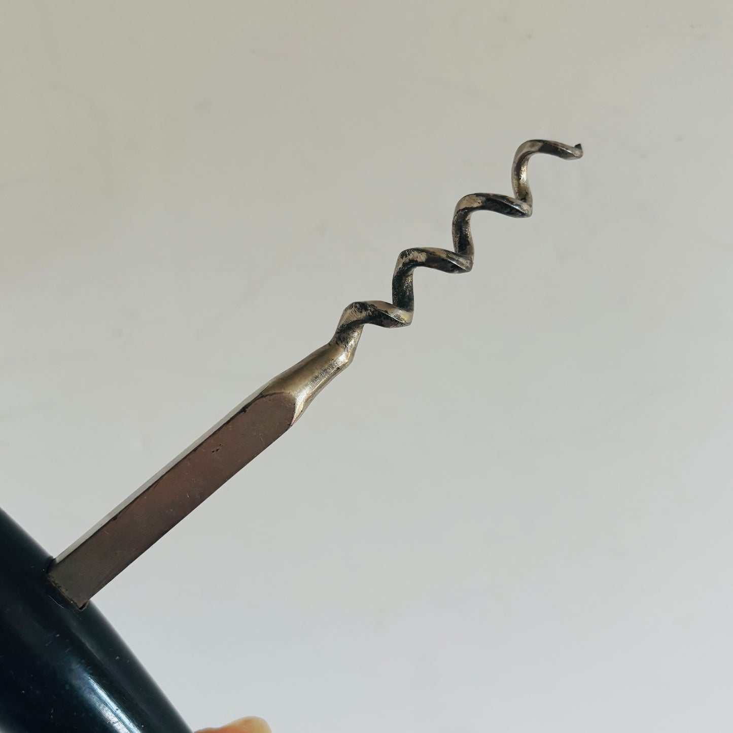 Corkscrew being used to open a bottle on a white background