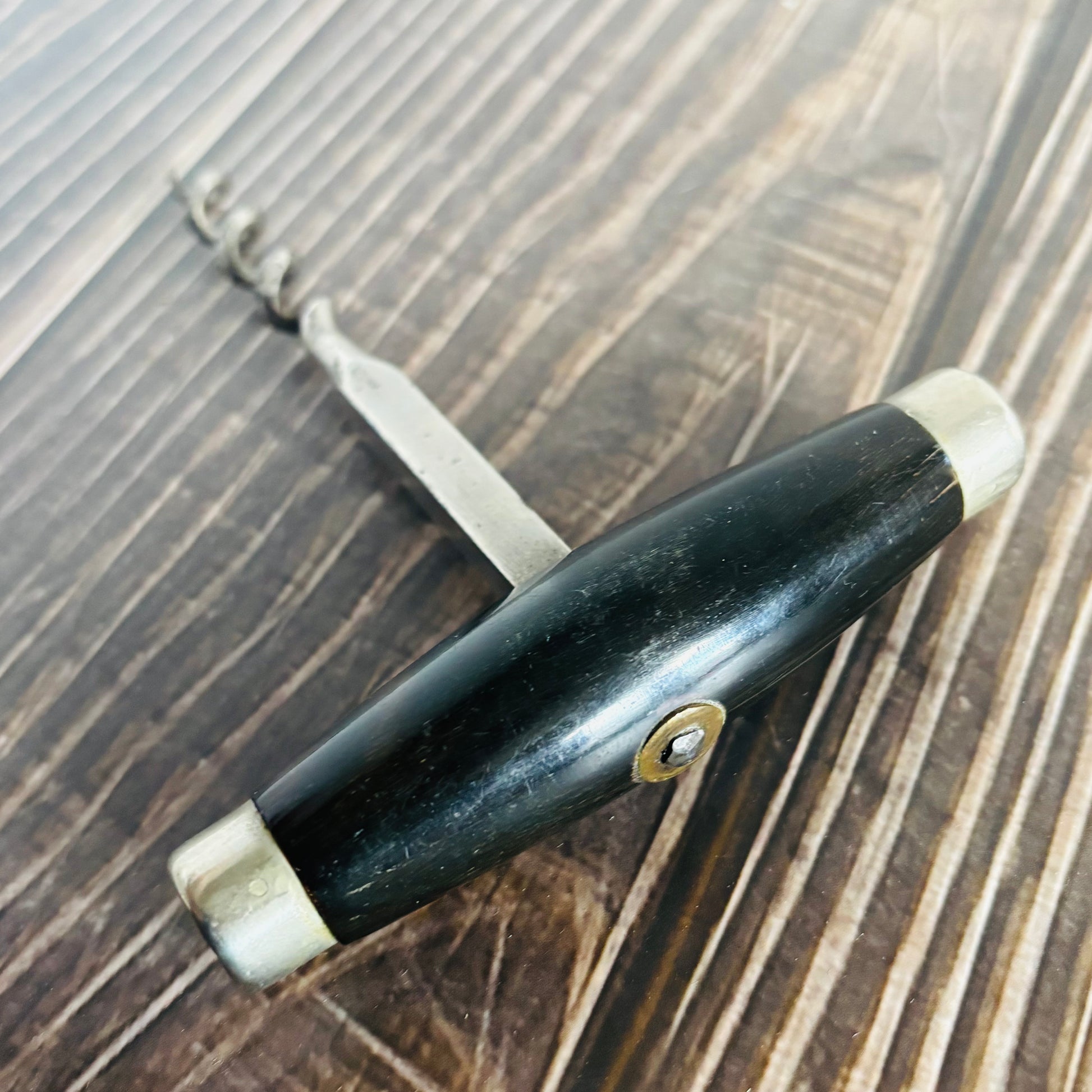 Black handled antique corkscrew on a wooden surface