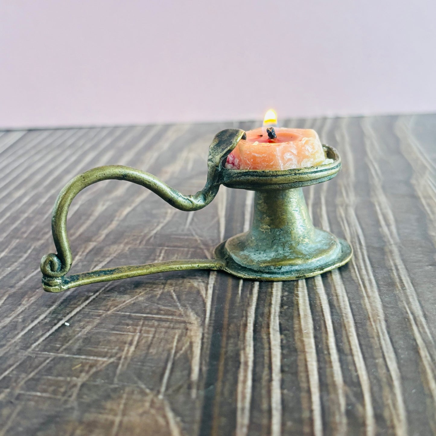 Antique Rare Indian Brass Diya Oil Lamp with a lit candle on a wooden surface