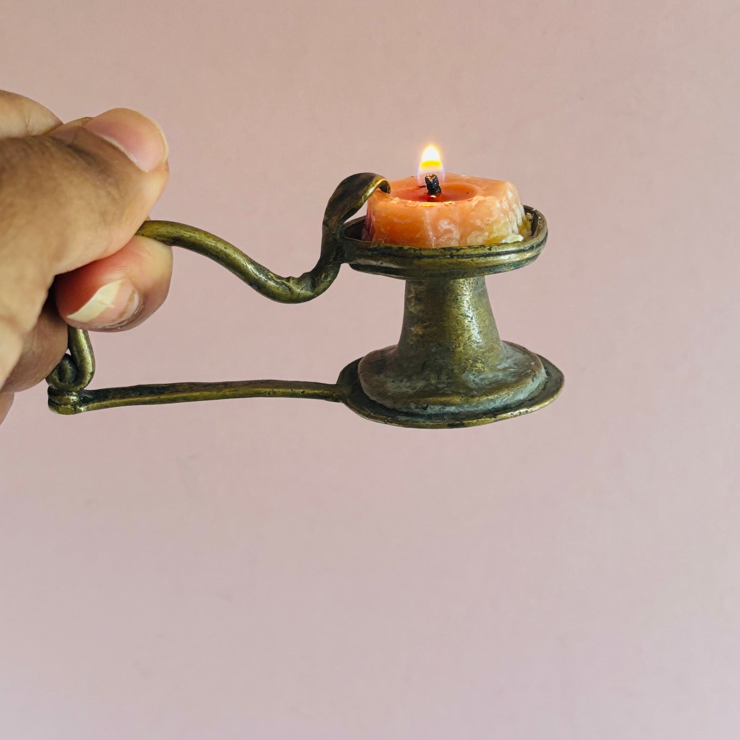 Hand holding an antique rare Indian brass Diya oil lamp with a lit candle 