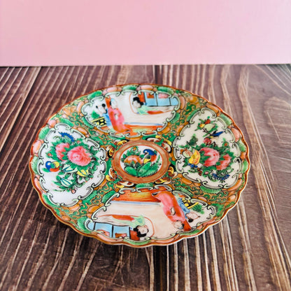 Decorative ceramic plate with colorful floral and landscape design on a wooden surface.