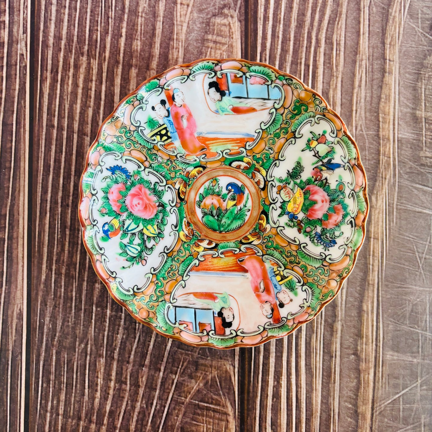 Decorative ceramic plate with colorful floral and animal patterns on a wooden surface