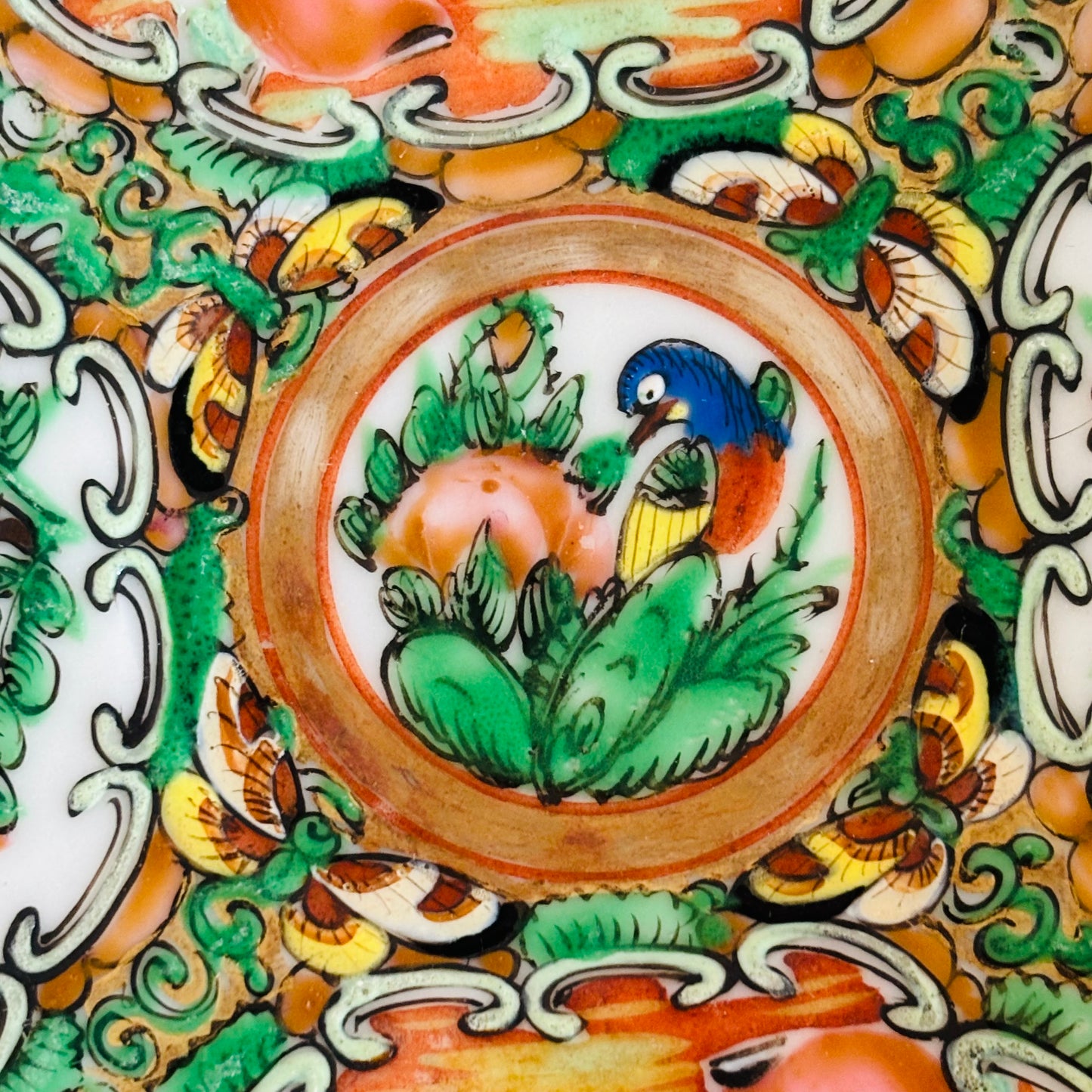 Decorative ceramic plate with a central design of a bird and leaves, surrounded by intricate patterns.