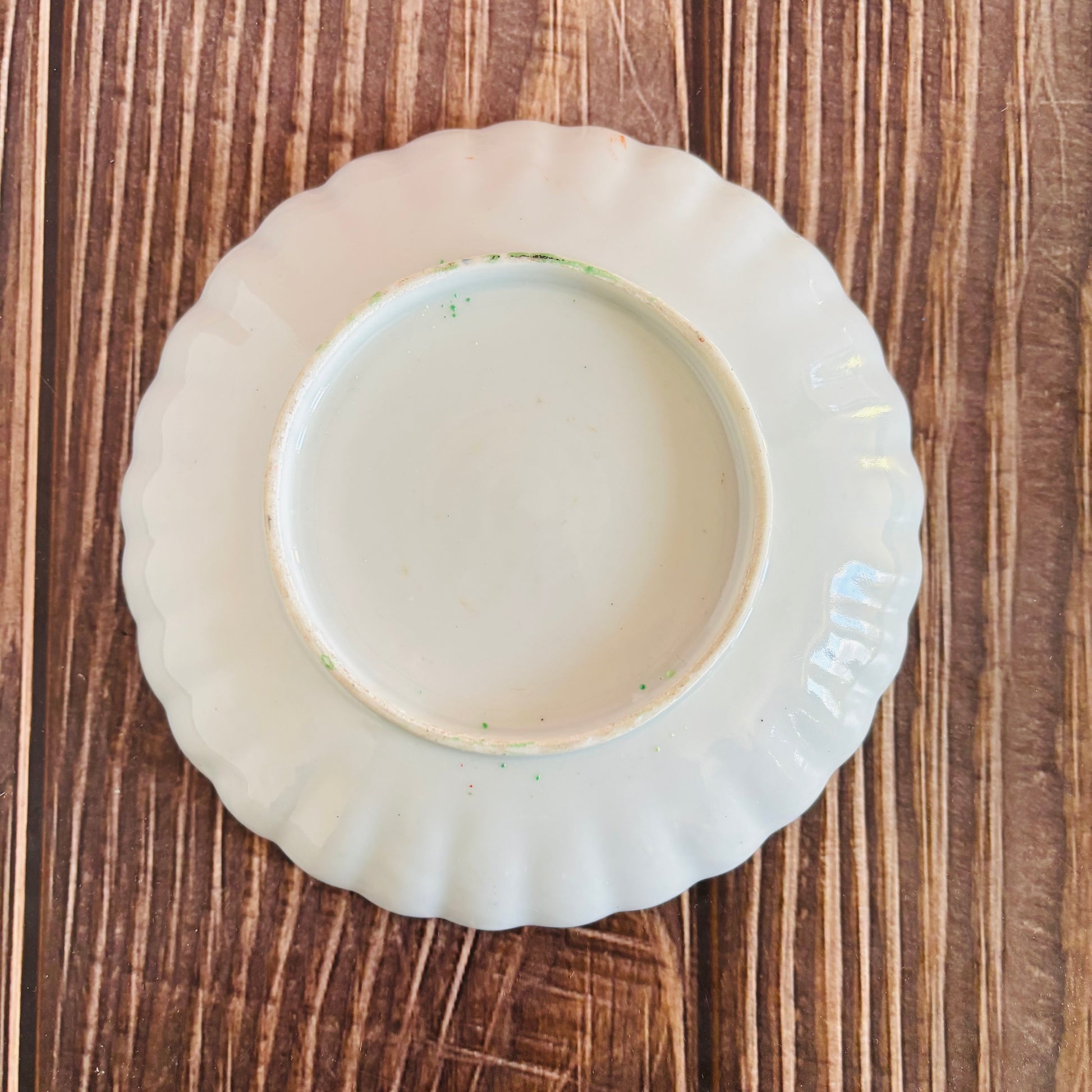White ceramic plate with scalloped edge on a wooden surface