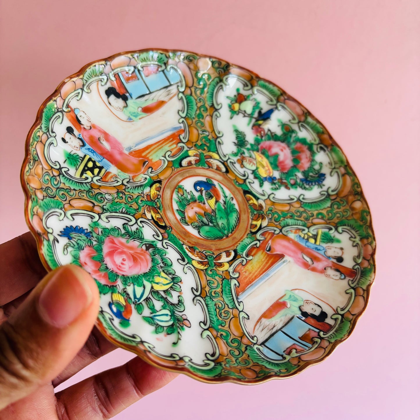 Decorative ceramic plate with intricate designs held against a pink background