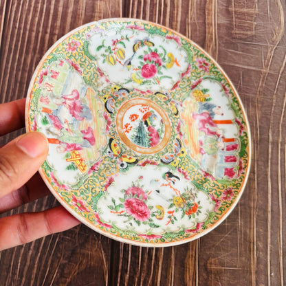 Decorative ceramic plate with intricate designs held by a hand on a wooden surface