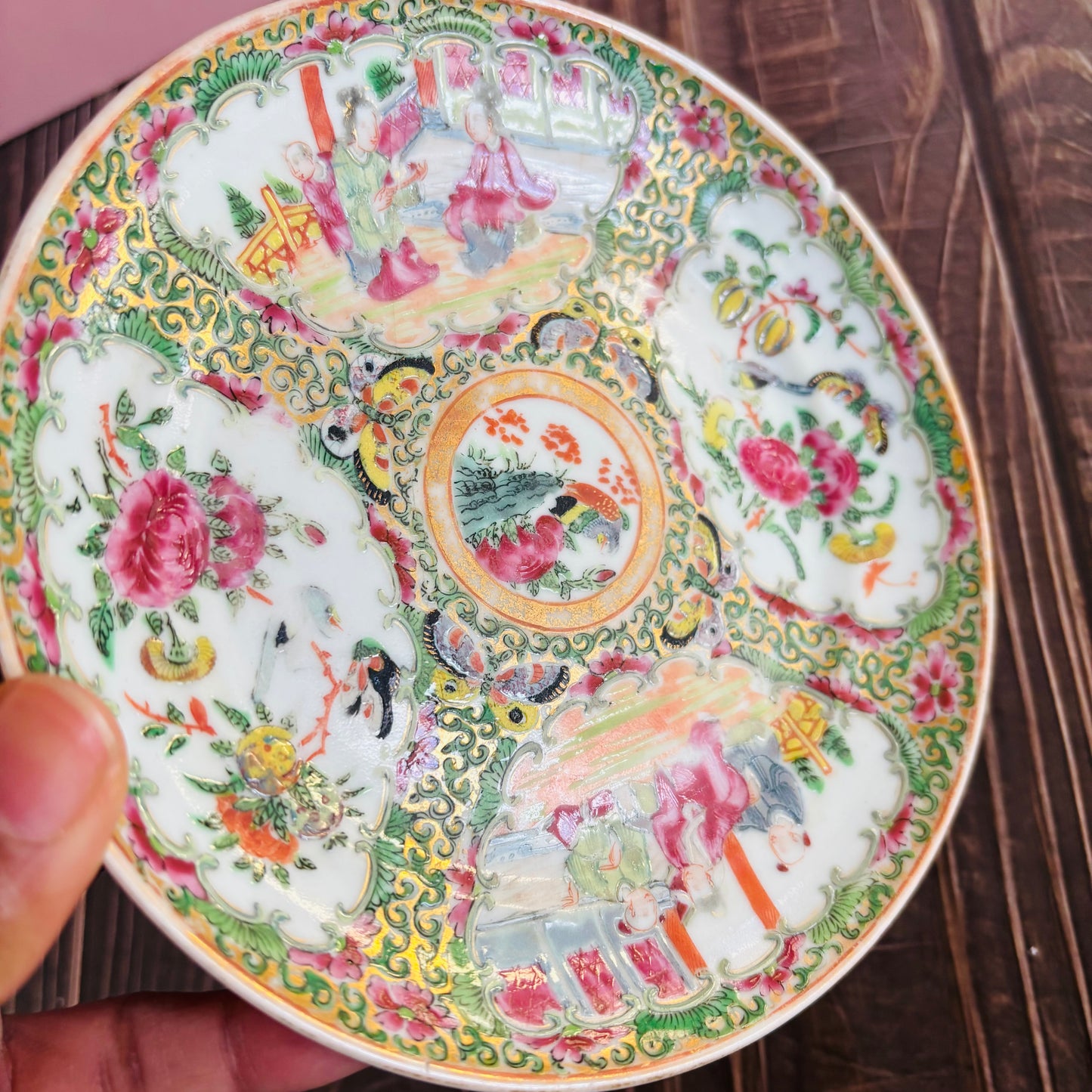 Decorative ceramic plate with intricate floral and animal patterns held by a hand.